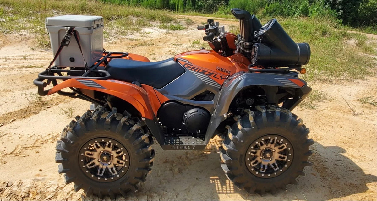 Side view of an orange Yamaha Grizzly with Lucky 7 high-clearance floorboards