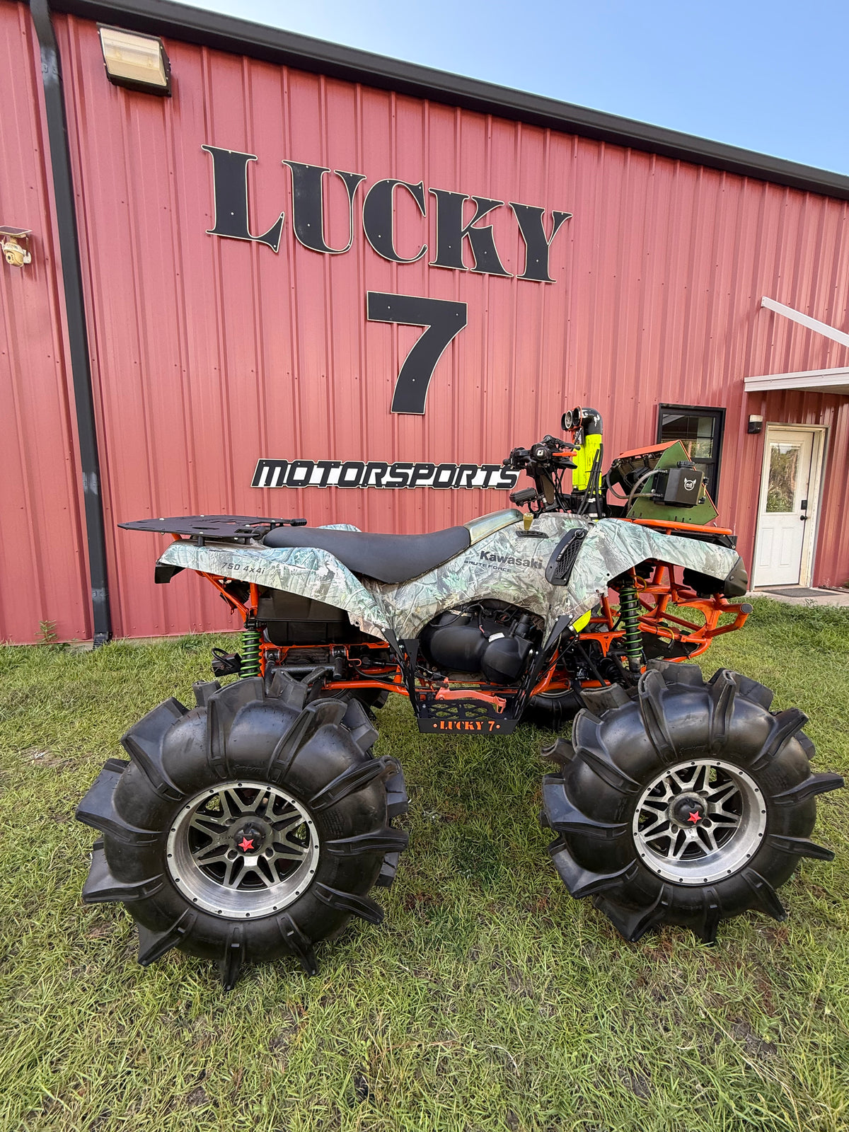 Orange Lucky 7 floorboards on a camo Kawasaki Brute Force in front of the Milton shop